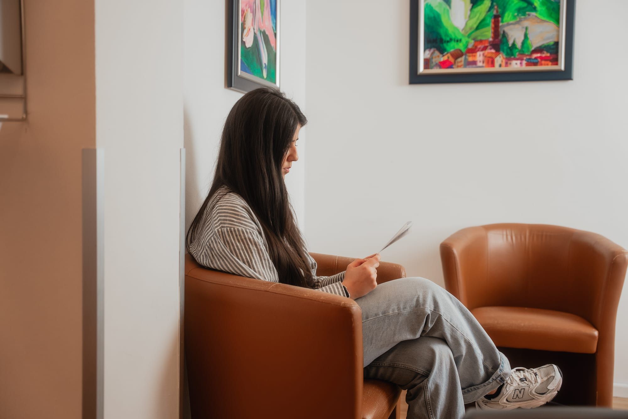 Patientin liest im Wartesessel — ruhige Atmosphäre vor dem Gespräch